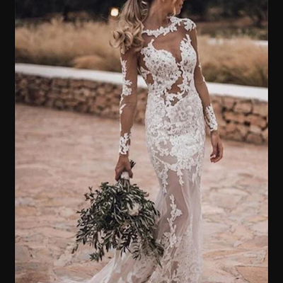 Noiva a usar vestido de noiva rendado com efeito ilusão, mangas compridas transparentes e silhueta ajustada, num ambiente exterior rústico