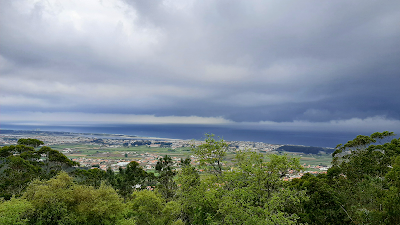Paisagem de arvores, um céu azul e o mar ao longe. Vista do ponto mais alto de Castro de São Lourenço.