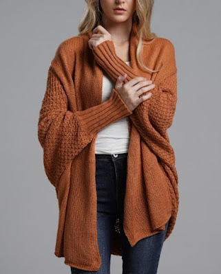 Mulher com cardigan castanho oversized, blusa branca e calças de ganga escuras, look casual e confortável ideal para o outono.