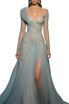 Modelo a usar um vestido de gala longo na cor azul-acinzentado ou azul-serenity. O vestido possui decote em V profundo, mangas longas transparentes e detalhes assimétricos em tule drapeado que cruzam o corpo. Apresenta ricos bordados florais prateados, transparências subtis no tronco e uma fenda lateral profunda na saia fluida.
