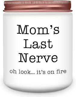 Uma vela aromática em frasco de vidro branco com tampa metálica acobreada, exibindo o rótulo humorístico em inglês: "Mom's Last Nerve - oh look... it's on fire" (A última paciência da mãe - oh olha... está a arder).