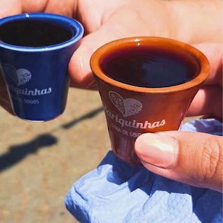 Duas mãos seguram copos de chocolate com licor de Óbidos durante a Feira Medieval de Santa Maria da Feira 2024.