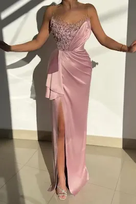 Woman wearing a long pink evening gown with a sparkling bodice, side draping, and a dramatic thigh-high slit.